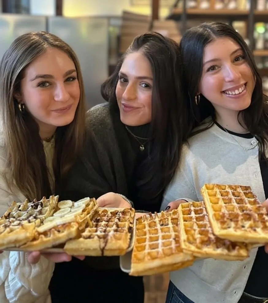 Three friends holding fresh Belgian waffles